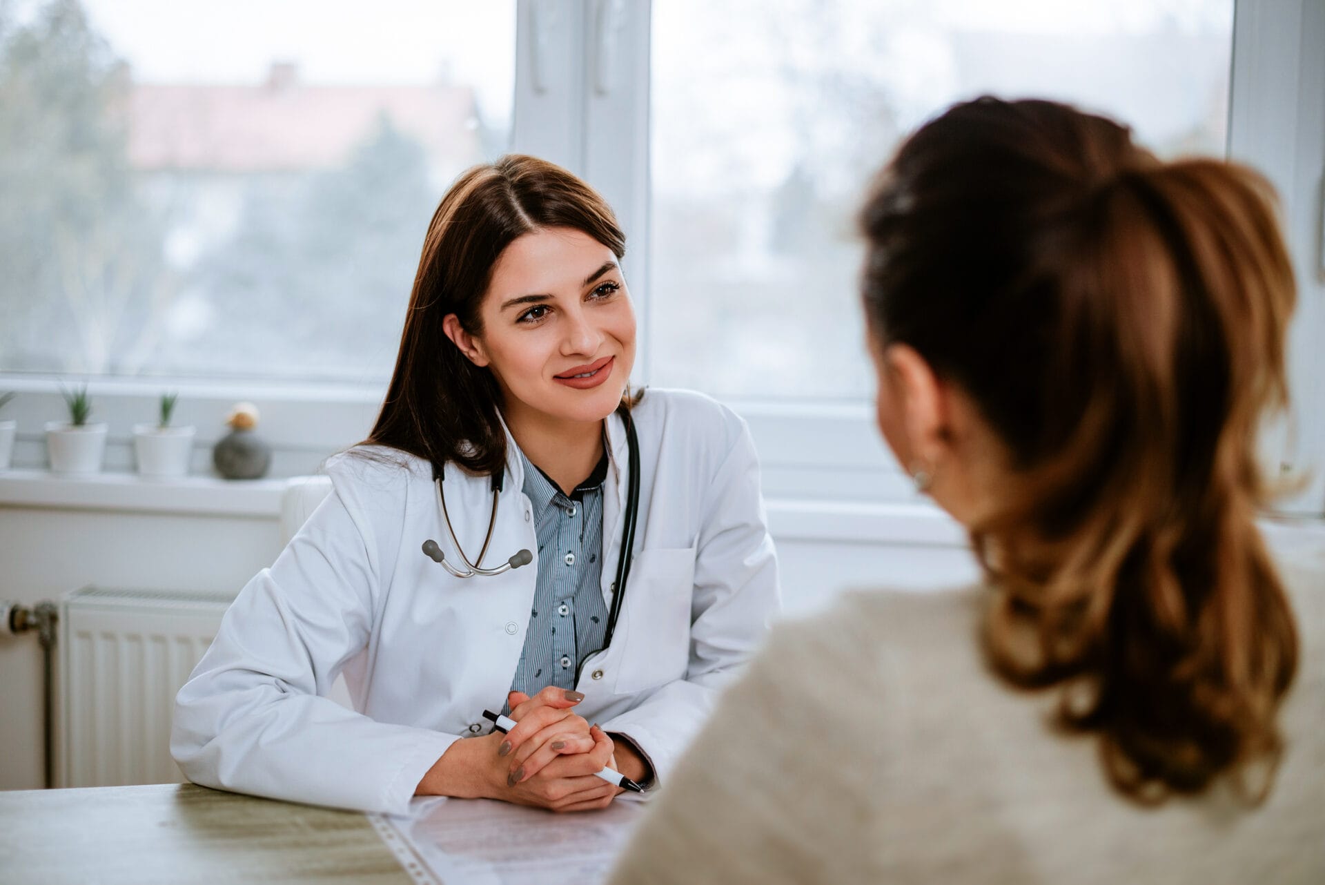 Cheerful young doctor listening to a patient in the office.